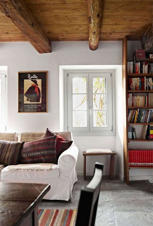 Decoración rústica con la alfombra estampada y los cojines con toques rojos que aportan color y carácter a este salón blanco y luminoso.