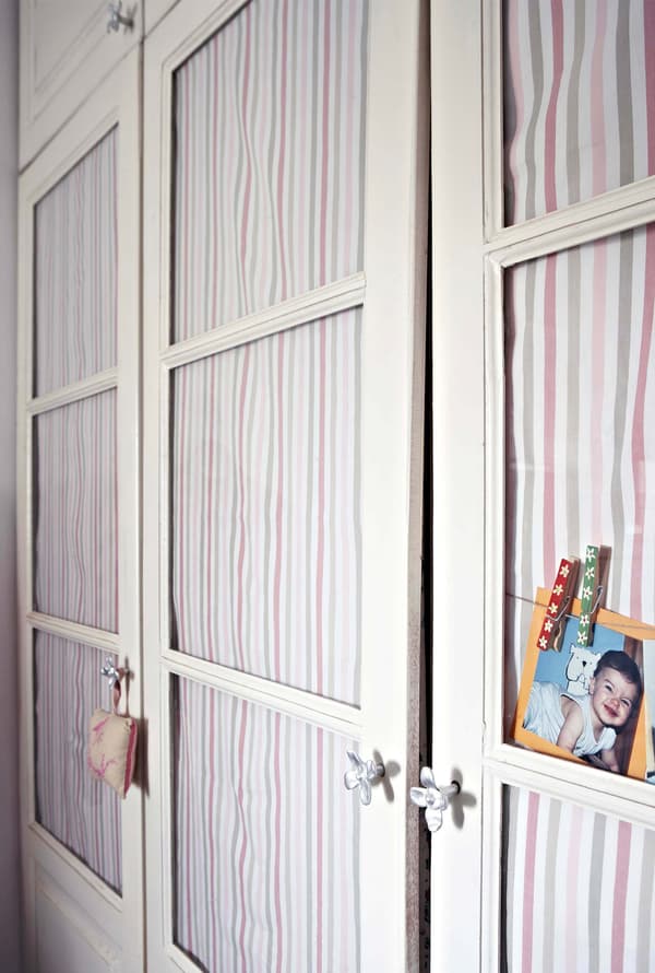 Decoración rústica con telas rotas colgadas en las puertas de un armario de cristal para esconder la ropa.