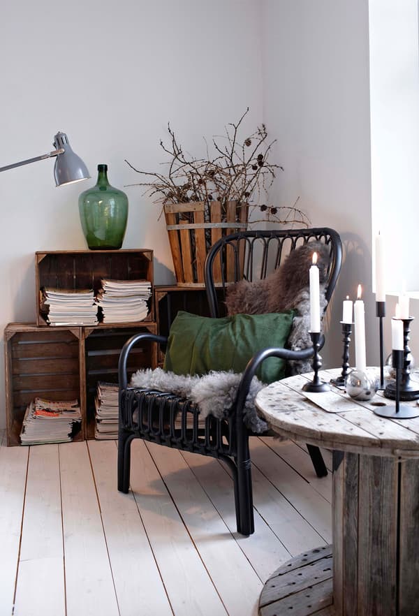 Decoración rústica con toques verde oscuro del jarrón y el cojín complementan los muebles de madera natural en este salón blanco.