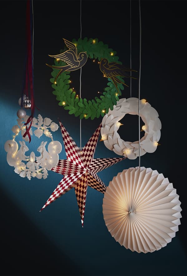Décorations festives et lanternes en papier accrochées au plafond, sur fond bleu foncé.