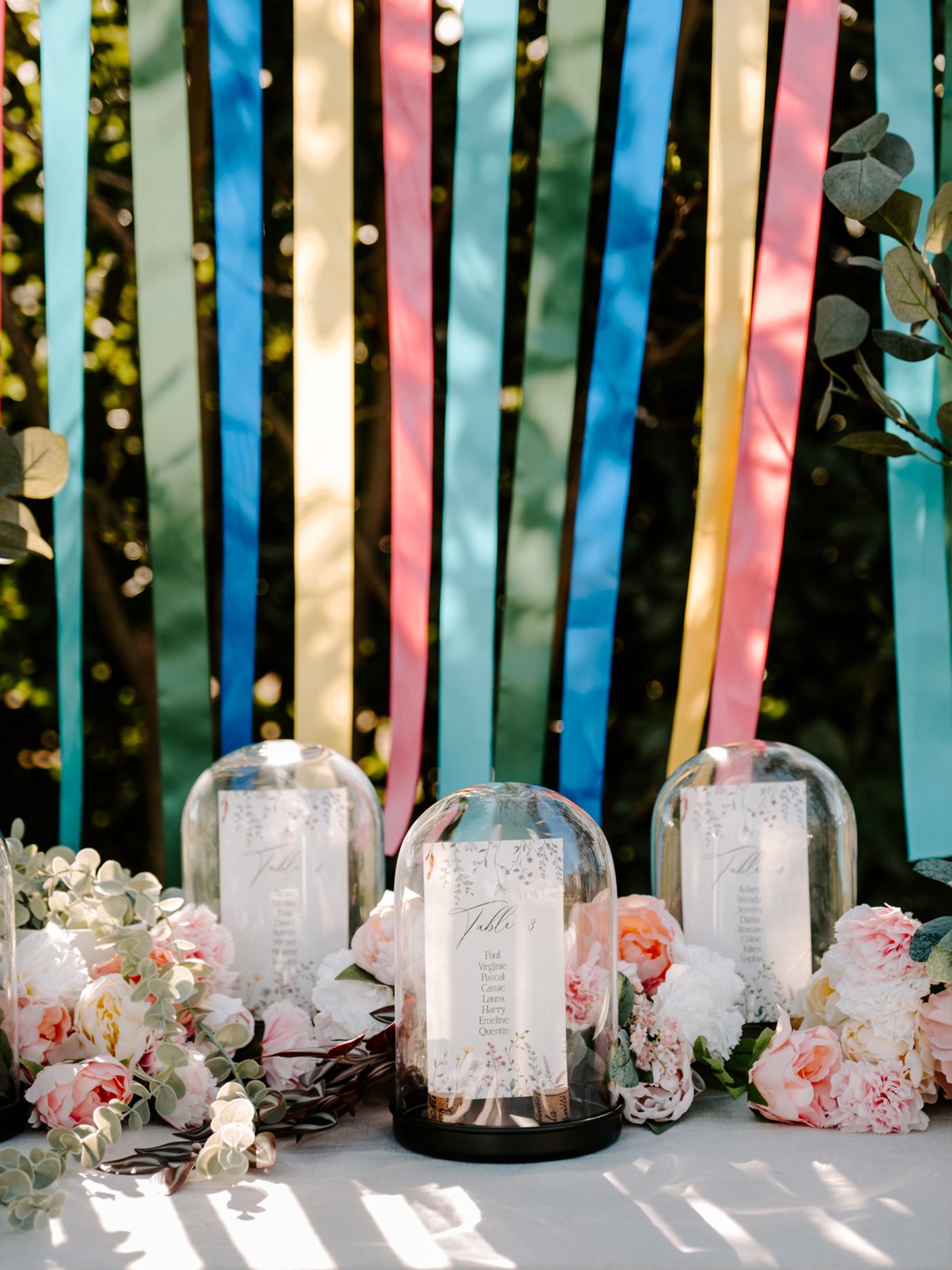 Décorations sous cloche en verre disposés sir une table décorée de fleurs roses