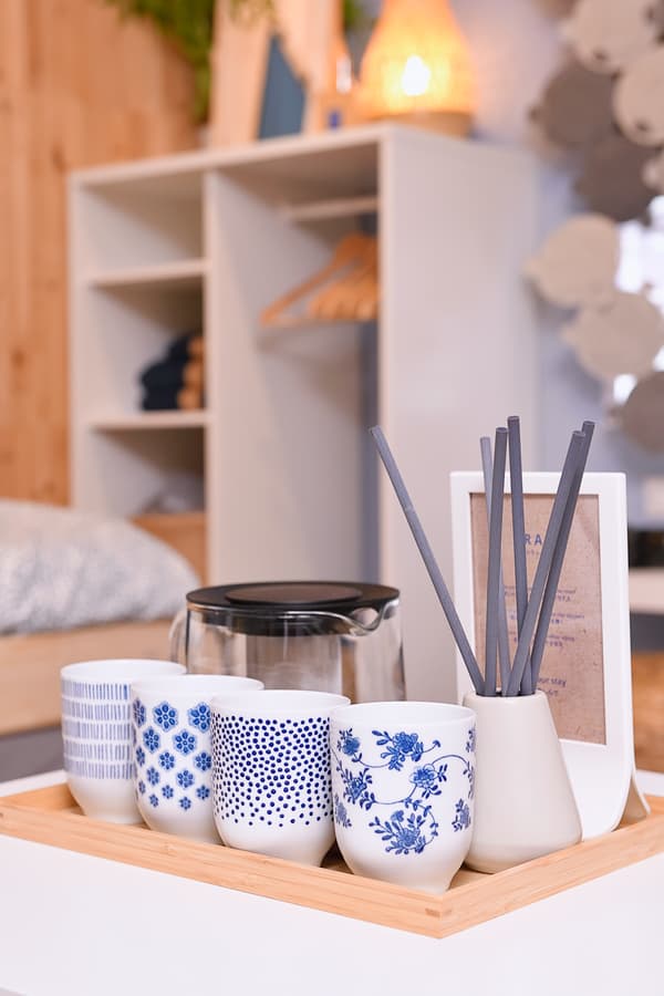Decorative cups, a jug and a diffuser are placed on a wooden tray.