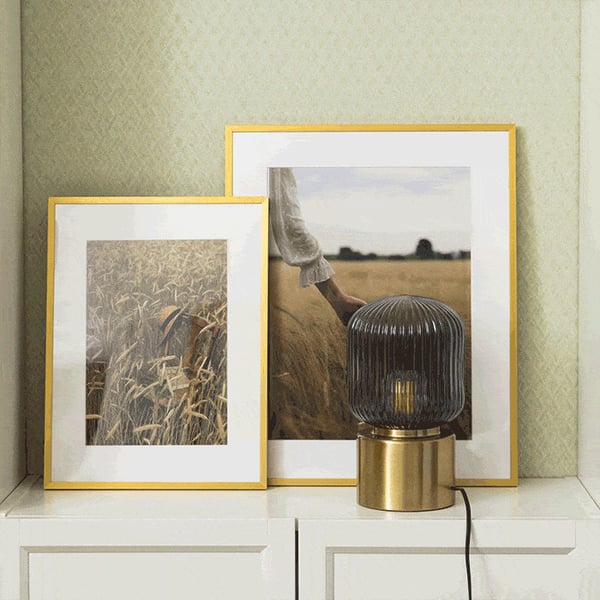 Decorative shelf styling with framed photographs and modern table lamp