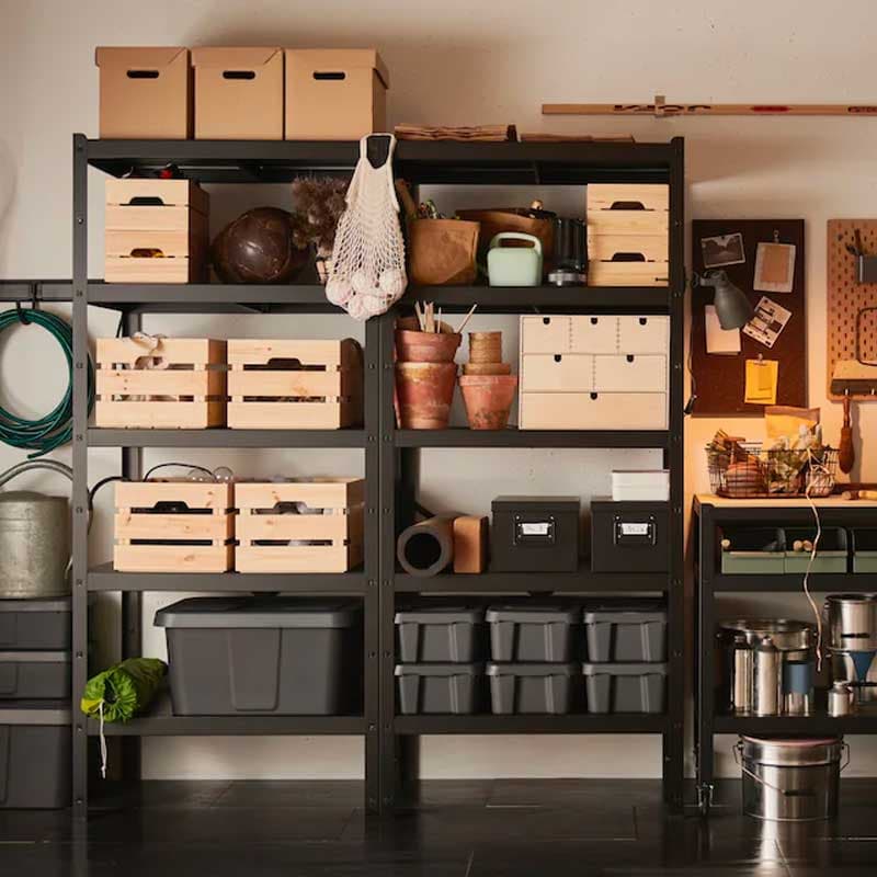 Degli scaffali nerio BROR con contenitori di cartone, legno, nere e due bacheche illuminate sulla destra.