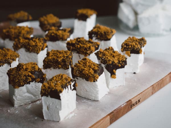 Dekorerade marshmallows står uppradade på en skärbräda.