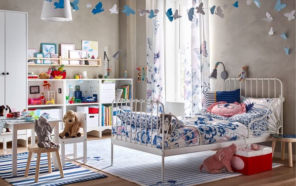 Dekoriere dieses Zimmer mit dem ausziehbaren MINNEN Bettgestell mit Federholzrahmen in Weiß durch Textilien unserer neuen SÅNGLÄRKA Serie, die Bettwäsche mit Blütenmuster und transparente Gardinen mit blauen und rosafarbenen Schmetterlingen bietet.