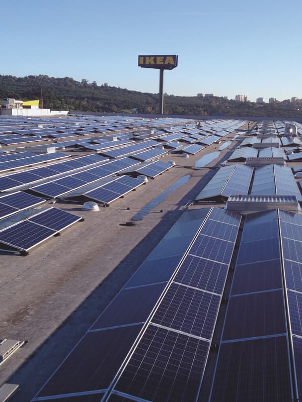 Des centaines de panneaux solaires sur le toit d’un bâtiment IKEA. À l’arrière-plan on distingue la grande enseigne IKEA à trois faces.