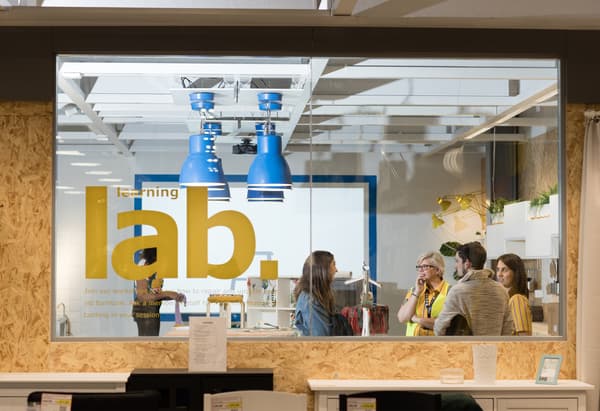 Des collaborateurs IKEA parlent à des clients derrière une vitre sur laquelle est écrit ‘learning lab’.