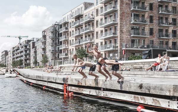 Des enfants sautant dans l'eau et des immeubles à appartements à l'arrière-plan.