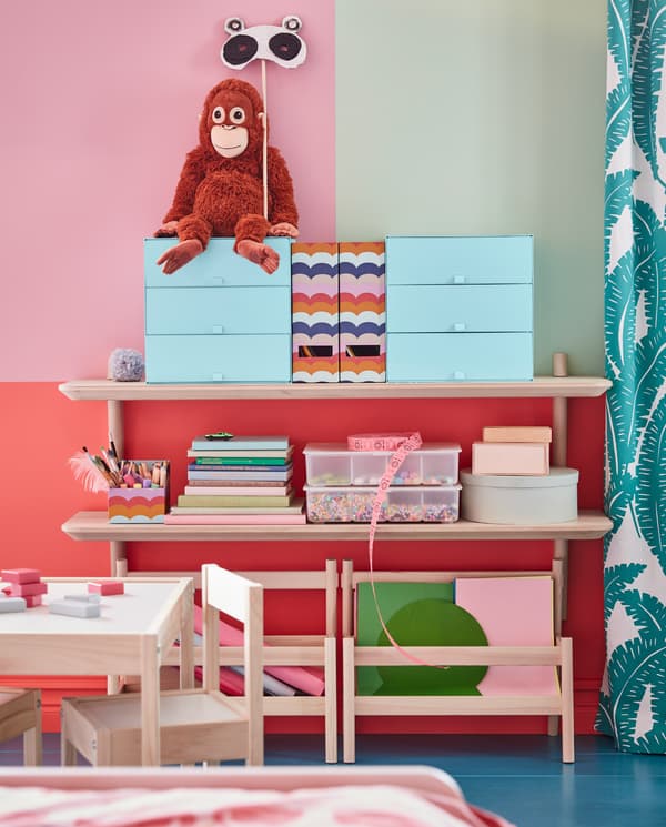Des étagères murales plaquées frêne LISABO qui accueillent des boîtes de rangement colorées, un orang-outan en peluche, des livres et des bricolages.