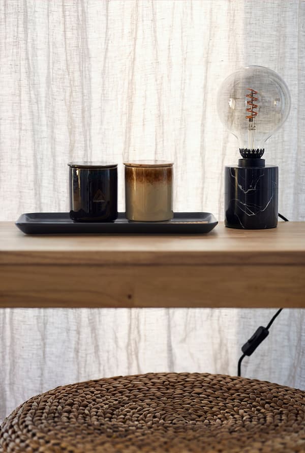 Des objets de décoration et une lampe posés sur un banc en bois massif.