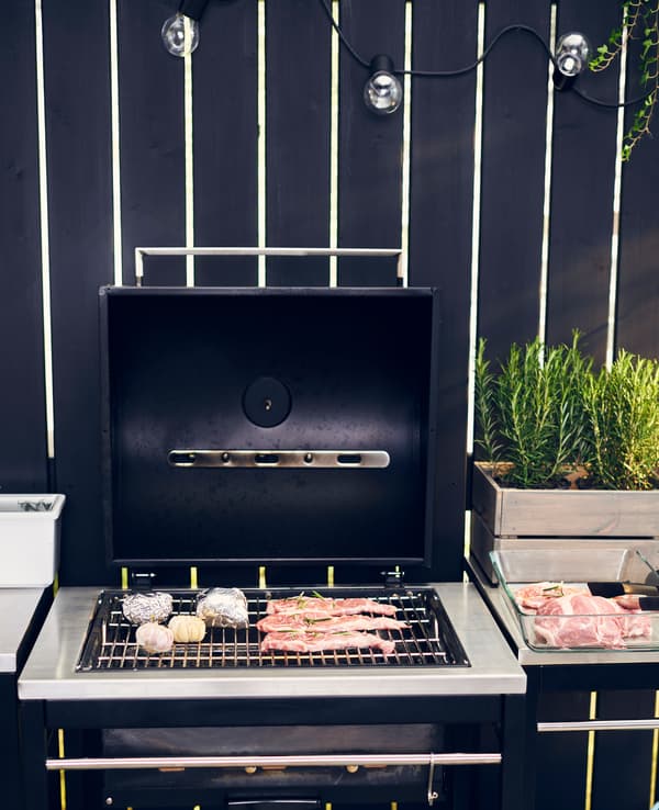 Des pièces de viande et quelques têtes d’ail cuisent sur le grill, d’autres morceaux attendent leur tour juste à côté