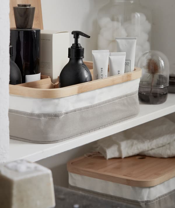 Des produits de beauté ordonnés dans une boîte à compartiments, sur une tablette de pair avec d’autres articles de rangement.
