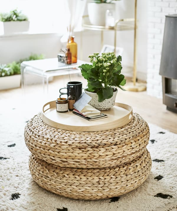 Des repose-pieds en rotin empilés et utilisés comme tables d’appoint.