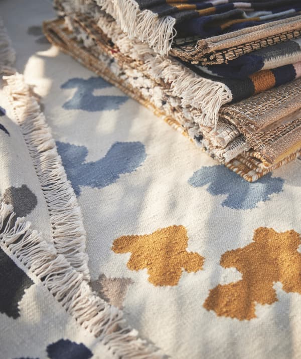 Des tapis empilés sur un tapis blanc avec des motifs bleus et jaunes.