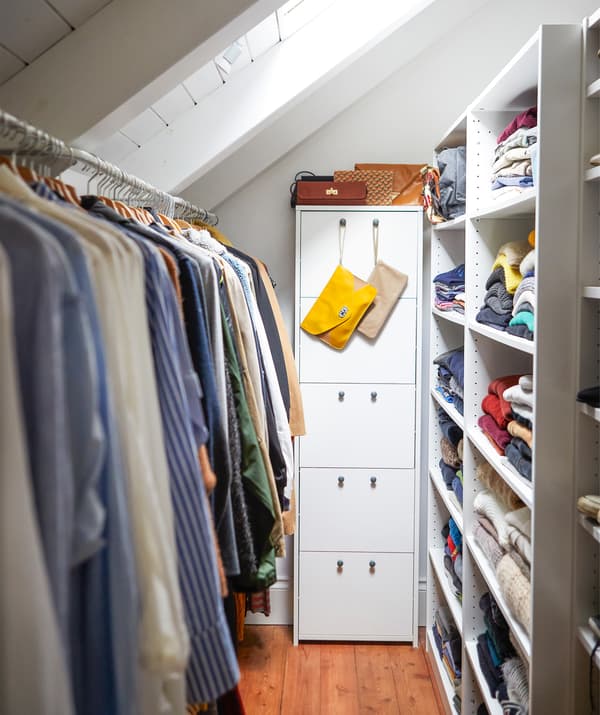 Des vêtements dans un rangement étroit avec des tiroirs, des étagères et des tringles.