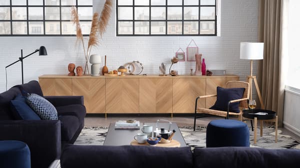 Design-Wohnzimmer mit 3er-Sofa, 2er-Bettsofa, Aufbewahrungskombination mit Türen und einem Sessel.