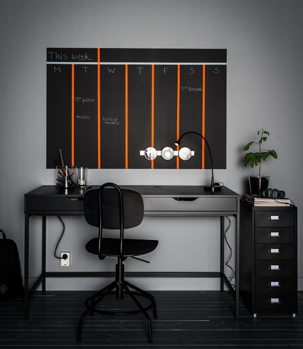 Desk organisation with drawer inserts, magnetic containers and a painted wall calendar above a grey desk with two drawers.