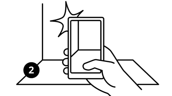 Dessin en noir et blanc portant le numéro 2 d’une main tenant un smartphone et prenant en photo une pièce vide.