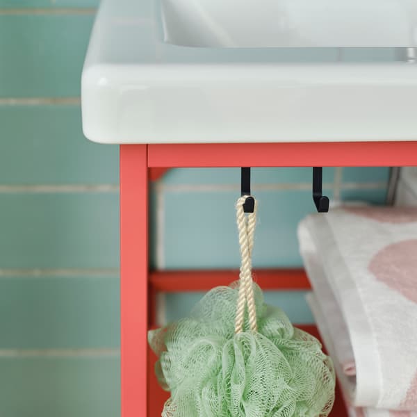 Detail černých háčků na červeném dílu ENHET v koupelně