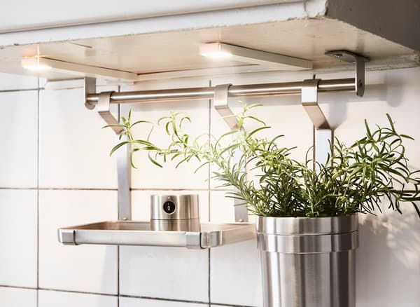 Detail of a KUNGSFORS stainless steel rail with a cooking timer and herbs in pots under battery-operated lighting.