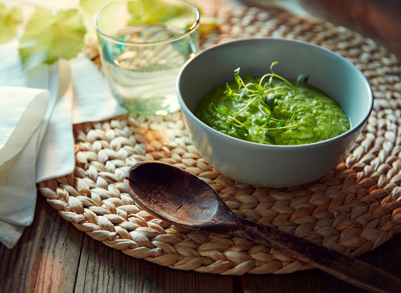 Detail prostírání SOARÈ, na ní leží dřevěná lžíce, sklenice s vodou a miska
