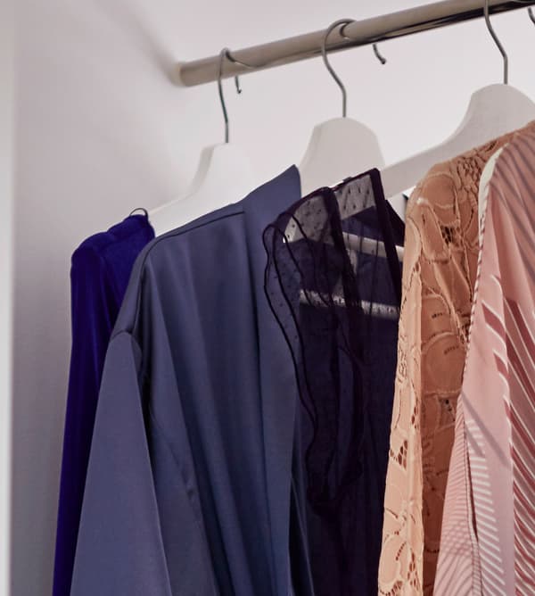 Detail showing clothing hung on a clothes rail in a white wardrobe.