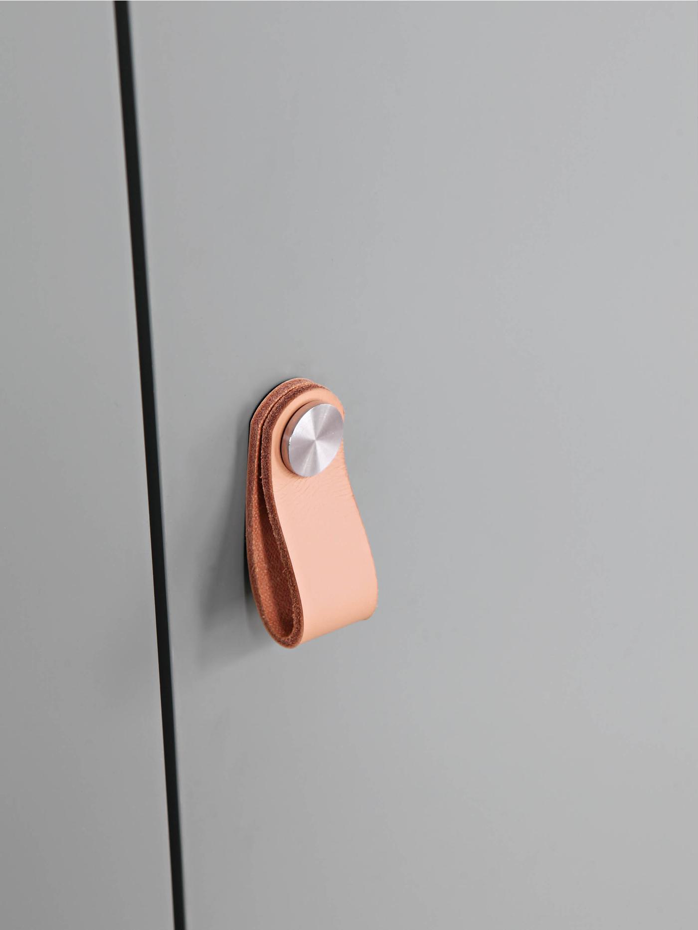 Detaljbilde av et skapdørhåntak i skinn.