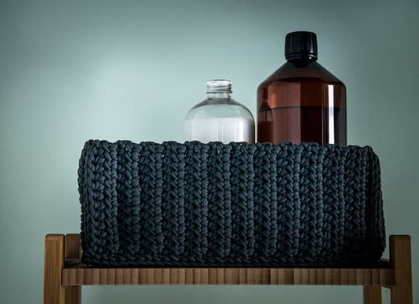 Detall d'un cistell de tela negra amb productes de bany.