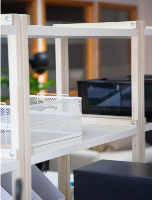 Detall d’una estructura de prestatgeria amb safates organitzadores blanques i negres en un entorn d’oficina.