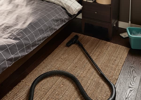 Detalle de alfombra en una habitación sobre la cual hay una aspiradora.