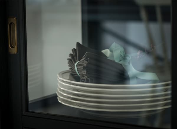 Detalle de pratos brancos e panos de mesa de tea nunha vitrina.