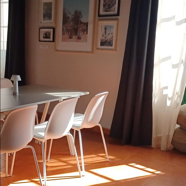Detalle de sala de reuniones con sillas blancas y una ventana con cortinas.