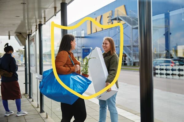 Deux amis portant leurs courses IKEA à la sortie du magasin