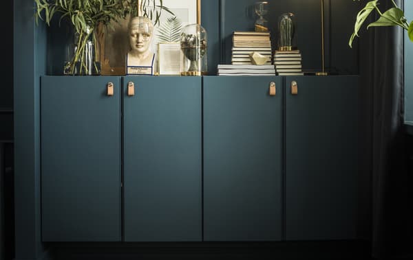 Deux armoires IVAR peintes dans la même teinte que les murs, garnies de livres, œuvres d’art et plantes, avec une lampe posée dessus. 