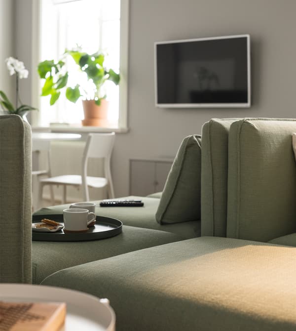 Deux canapés modulaires placés dos à dos et une TV fixée au mur.