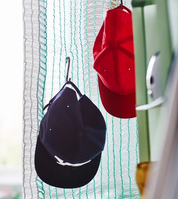 Deux casquettes de base-ball accrochées à des S fixés à un filet de volley.