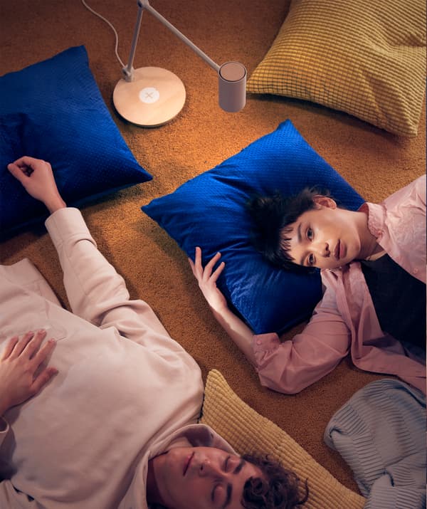 Deux copains couchés par terre et se relaxant sur des coussins dans une chambre d'étudiant.