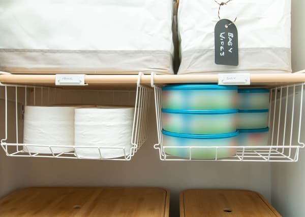 Deux corbeilles à pinces OBSERVATÖR blanches installées sur une tablette et contenant des rouleaux de papier hygiénique et des fournitures pour bébé.