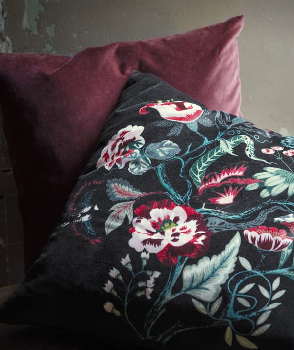 Deux coussins en velours, l'un rouge, et l'autre foncé et décoré de fleurs.