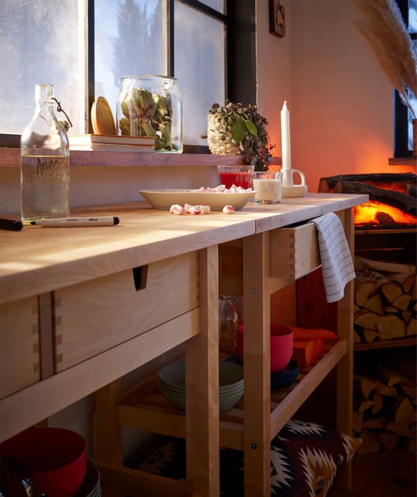 Deux dessertes le long du mur qui forment une longue table d’appoint sur laquelle se trouvent des bougies et une assiette de friandises d’après-repas.