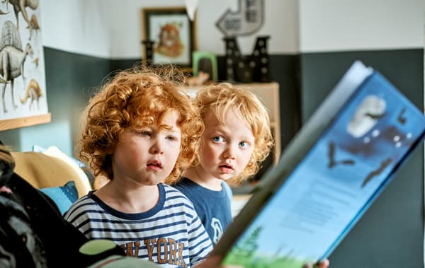 Deux enfants à qui l'on fait la lecture dans un livre bleu.