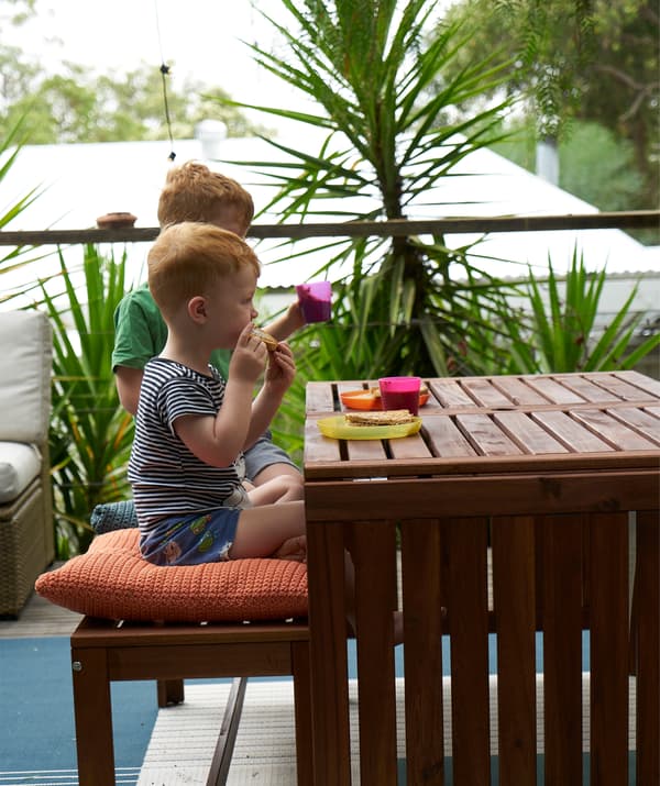 Deux enfants occupés à manger à une table à l'extérieur.