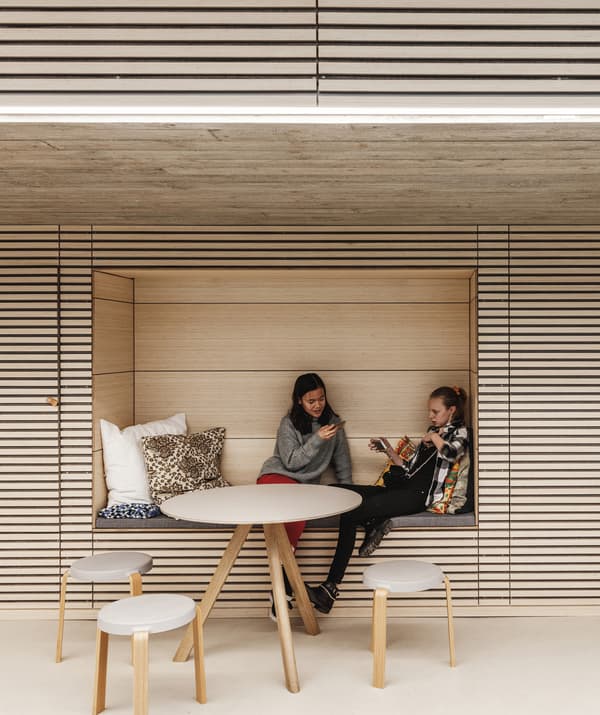 Deux femmes assises dans une niche d'un mur lambrissé, derrière une table et des chaises.