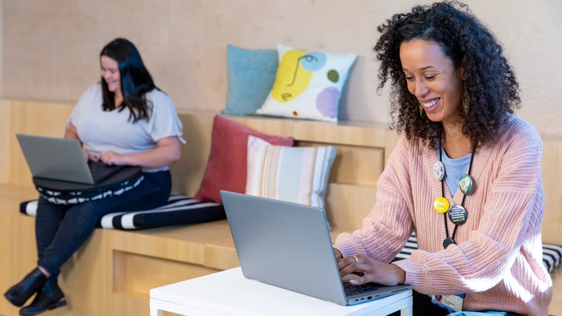 Deux femmes souriantes se servant de leurs ordinateurs portables.