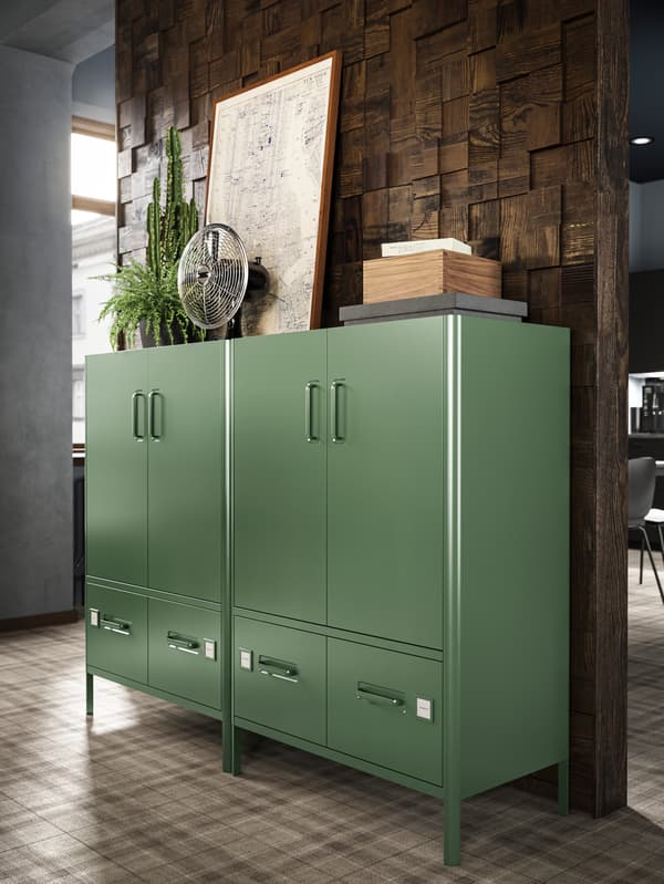 Deux grands rangements IDÅSEN verts avec portes et tiroirs l’un à côté de l’autre dans un espace de travail à l’éclairage chaleureux.