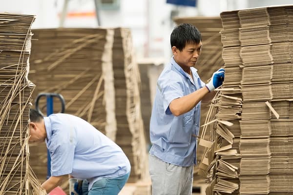 Deux hommes organisant des piles de boîtes en carton chez un fournisseur IKEA.