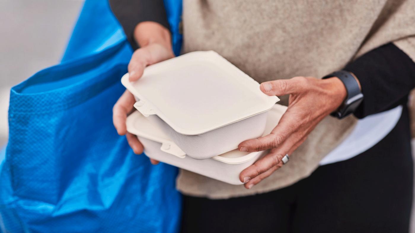 Deux mains qui tiennent des plats de nourriture pour emporter.