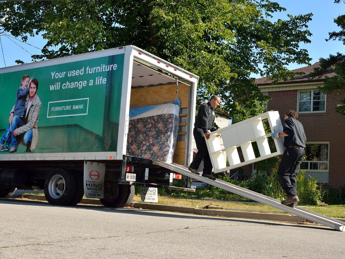 Deux personnes transportant un KALLAX à l’intérieur d’un camion de la banque de meubles.