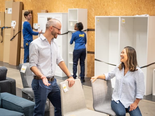 Deux personnes traversent une rue en portant une étagère KALLAX d’IKEA.